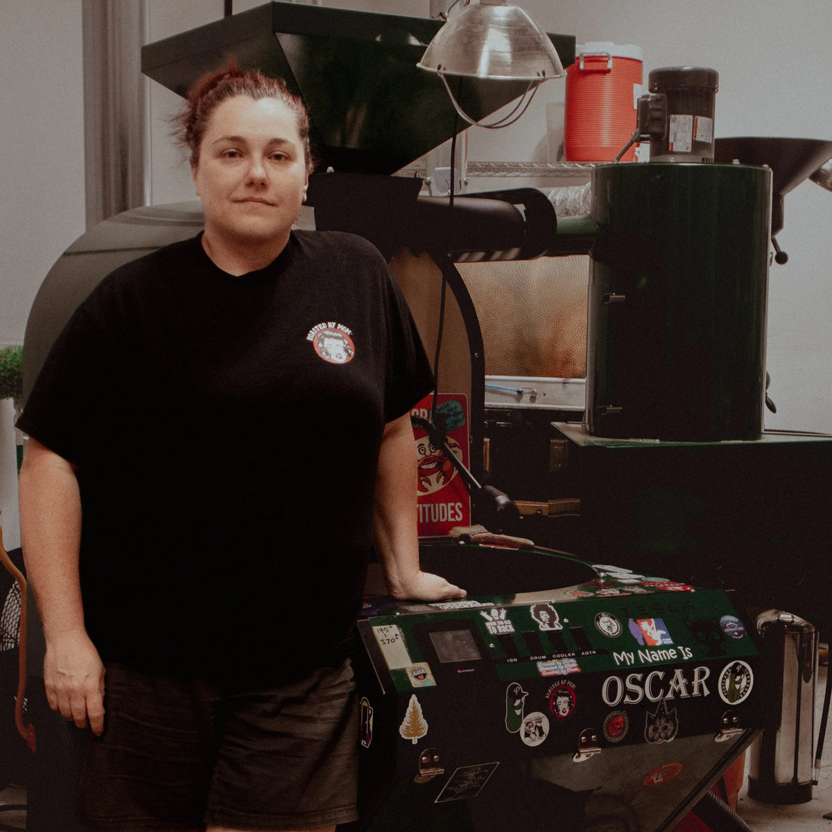 Person wearing a black t-shirt with a logo, standing in a kitchen or food preparation area.